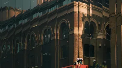 Ouvriers sur nacelle devant une facade vitrée reflétant un bâtiment ancien